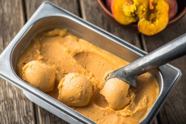 Ahşap masa kaşık ile kapsayıcısında şeftali dondurma