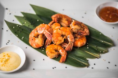 Kızarmış karides yapraklarda beyaz zemin üzerine sos ile servis