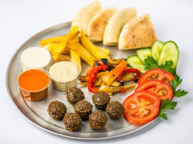 Tabak vejetaryen yemek oryantal tarzı: falafel, ızgara biber, pide, domates, salatalık, patates, Humus, beyaz zemin üzerine metal tabakta soslar