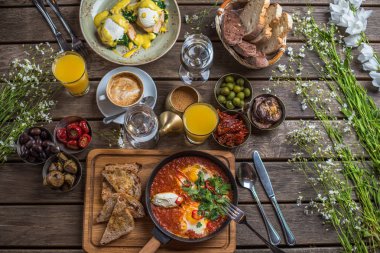 shakshuka, zeytin, biber, domates, ekmek, meyve suyu ve kahve rustik ahşap tablo ile kahvaltı