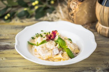 Krema soslu makarna çeşitleri ahşap masa üzerinde beyaz tabakta servis