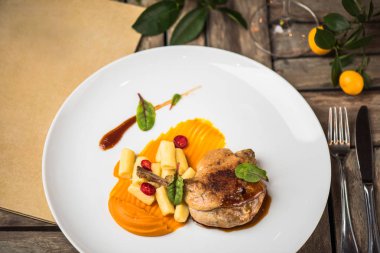 Ahşap masa üzerinde beyaz tabakta ördek bacak garnitür ile servis