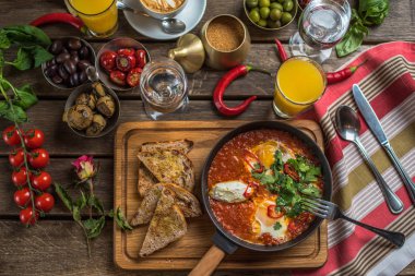 shakshuka, zeytin, biber, domates, ekmek, meyve suyu ve kahve rustik ahşap tablo ile kahvaltı