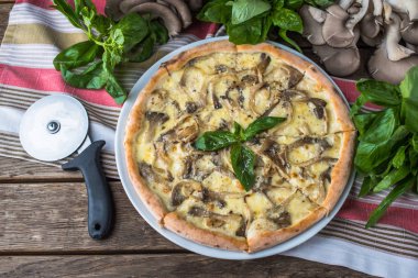 Mantarlı pizza ve ahşap masada fesleğen.