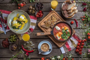 shakshuka, zeytin, biber, domates, ekmek, meyve suyu ve kahve rustik ahşap tablo ile kahvaltı