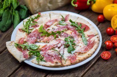 Roka ve ahşap masa tabakta servis jambon ile İtalyan pizza