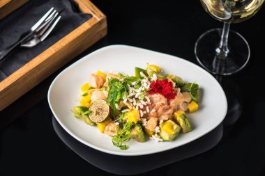 İncelik sebze salatası kadeh beyaz şarap ile siyah arka plan üzerine tabakta servis