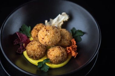 Derin kızarmış peynir topu yığılmış siyah kase sos ile servis