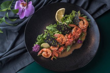 Hazır karides soslu taze yeşillik karanlık yüzeyinde siyah plaka üzerinde yatağa yılları arasında görev yapmıştır