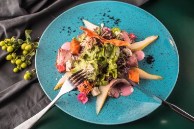 Kızarmış ördek karanlık yüzeyi mavi tabakta servis ile taze sebze salatası