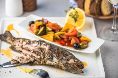 Izgara balık tabakta taze sebze salatası ve limon ile