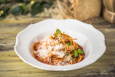 Ahşap masa üzerinde beyaz tabakta servis domates soslu makarna çeşitleri