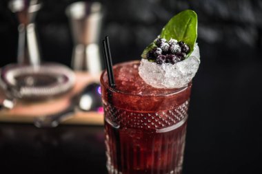 Yaprak ve koyu arka plan üzerinde yaban mersini taze kokteyl cam süslenmiş