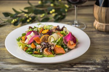 Ahşap masa üzerinde beyaz plaka üzerinde kızarmış tavuk ile sebze salatası