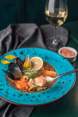 Deniz ürünleri tabak bardak beyaz şarap ile siyah kumaş üzerine mavi tabak içinde