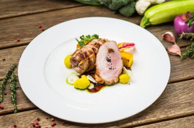 Beyaz ahşap masa üzerinde sebzeli tabakta kavrulmuş domuz eti