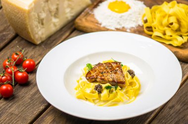 Izgara et ahşap masa üzerinde beyaz tabakta servis ile İtalyan Makarna