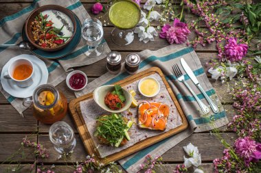 rustik ahşap masada servis edilen sandviç, smoothie, lapa ve atıştırmalıklar ile kahvaltı