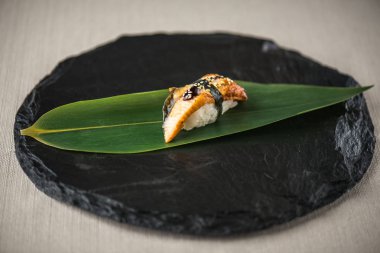Beyaz arka planda arduvaz üzerinde yaprak üzerinde yılan balığı ile geleneksel Japon Suşi