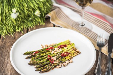 Biber ve beyaz tabakta fındık ile ızgara yeşil kuşkonmaz