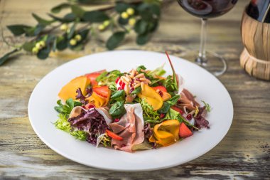 Ahşap masa üzerinde beyaz tabakta sebze salatası jambon ile hizmet