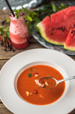 Çorba gaspaço taze karpuz ile ahşap masa beyaz tabakta servis