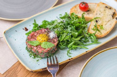 Çiğ yumurta sarısı ve salata tabağı yapraklarda ile et tartar snack