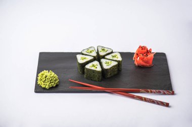 geleneksel gurme Japon üçgen suşi yemek çubukları, zencefil ve gri arka plan üzerinde kayrak gemide wasabi