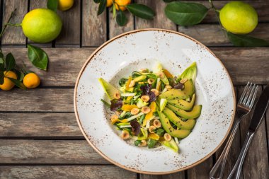 Taze salata avokado ve plaka üzerinde ahşap masa içinde fındık