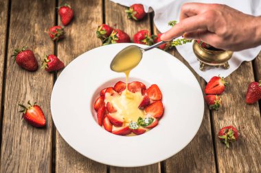 insan eli yağan taze çilek süt ile plaka üzerinde ahşap masaya jam