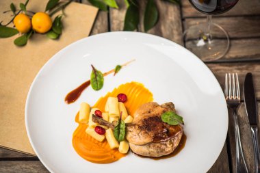 Ahşap masa üzerinde beyaz tabakta ördek bacak garnitür ile servis