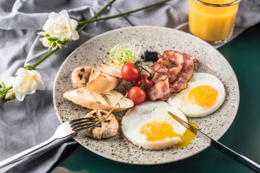 Kızarmış yumurta, pastırma, mantar ve bardak taze meyve suyu ile gri plaka üzerinde taze domates ile Servis Kahvaltı