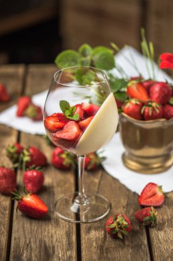Tatlı şarap cam ahşap masa üzerinde servis krem ve taze çilek ile