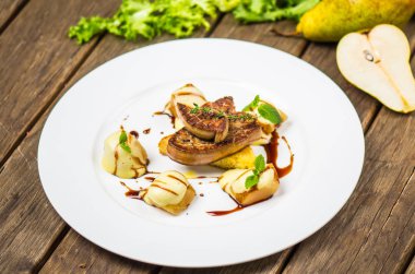 Izgara et ve ahşap masa üzerinde beyaz tabakta armut ile incelik çanak