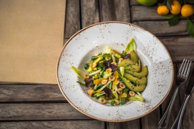 Taze salata avokado ve plaka üzerinde ahşap masa içinde fındık