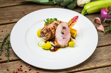 Beyaz ahşap masa üzerinde sebzeli tabakta kavrulmuş domuz eti