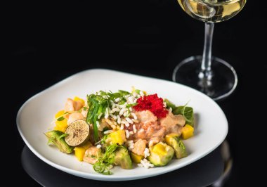 İncelik sebze salatası kadeh beyaz şarap ile siyah arka plan üzerine tabakta servis