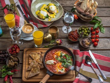 shakshuka, zeytin, biber, domates, ekmek, meyve suyu ve kahve rustik ahşap tablo ile kahvaltı