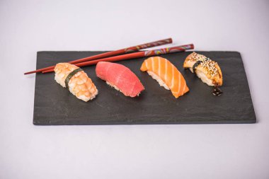 lezzetli nigiri suşi yemek çubukları ile gri arka plan üzerinde kayrak gemide görmek
