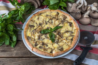 Mantarlı pizza ve ahşap masada fesleğen.