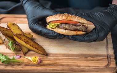 insan elinde hamburger kızarmış patates dilimleri ile tutarak lastik eldiven üzerinde ahşap kurulunda görev yapmaktadır.