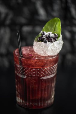 Yaprak ve koyu arka plan üzerinde yaban mersini taze kokteyl cam süslenmiş