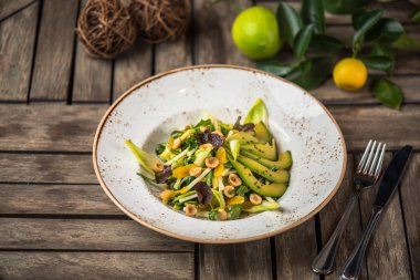 Taze salata avokado ve plaka üzerinde ahşap masa içinde fındık