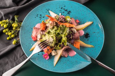 Kızarmış ördek karanlık yüzeyi mavi tabakta servis ile taze sebze salatası