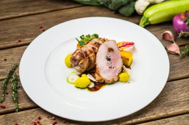 Beyaz ahşap masa üzerinde sebzeli tabakta kavrulmuş domuz eti