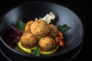 Derin kızarmış peynir topu yığılmış siyah kase sos ile servis