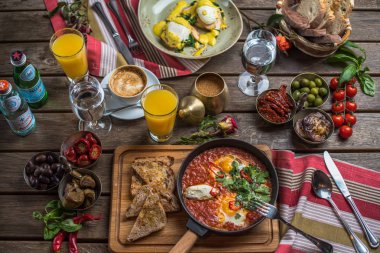 shakshuka, zeytin, biber, domates, ekmek, meyve suyu ve kahve rustik ahşap tablo ile kahvaltı