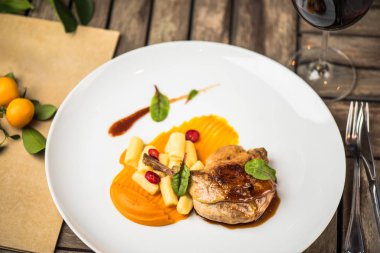 Ahşap masa üzerinde beyaz tabakta ördek bacak garnitür ile servis