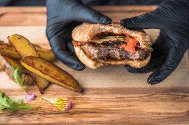 insan elinde hamburger kızarmış patates dilimleri ile tutarak lastik eldiven üzerinde ahşap kurulunda görev yapmaktadır.
