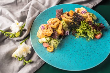 çiçeklerle mavi tabakta sebzeli krep haddelenmiş